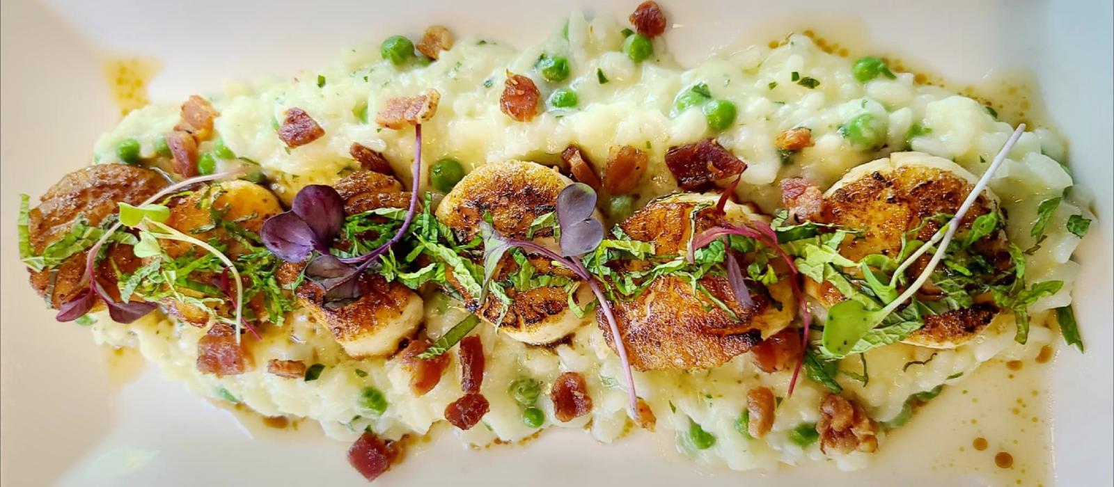 Seared scallops with Parmesan risotto, bacon crumbles and micro greens.